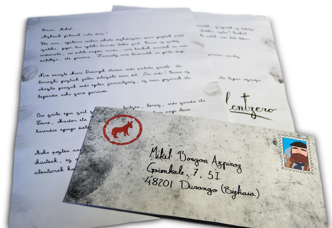 La carta de respuesta de Olentzero, con letra de pluma, junto a su sobre manchado de carbón