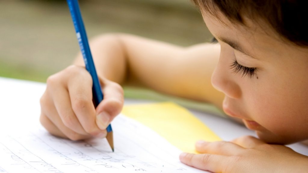 niño concentrado mientras escribe en un papel